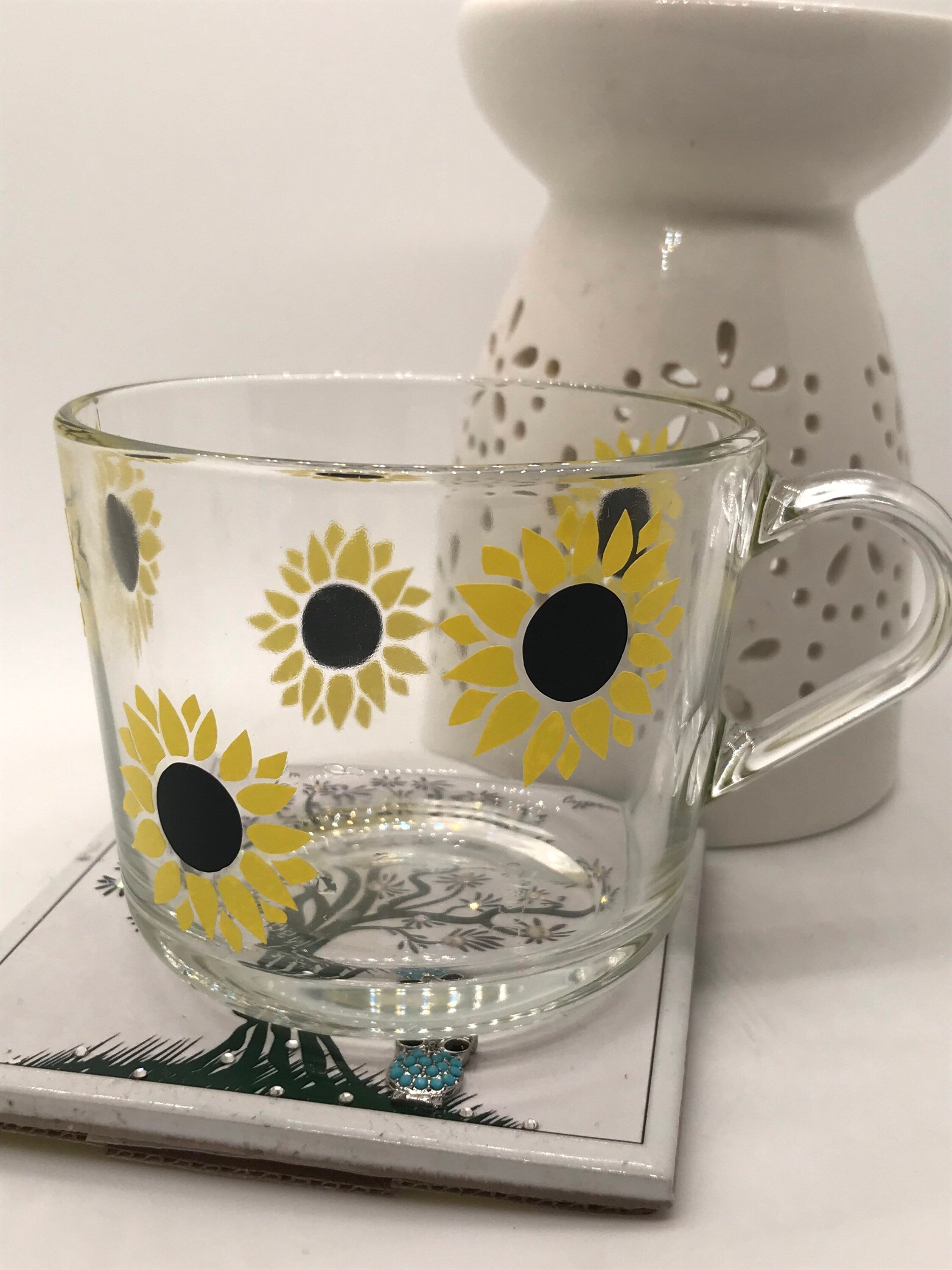 Clear glass mug with sunflower design on a white surface