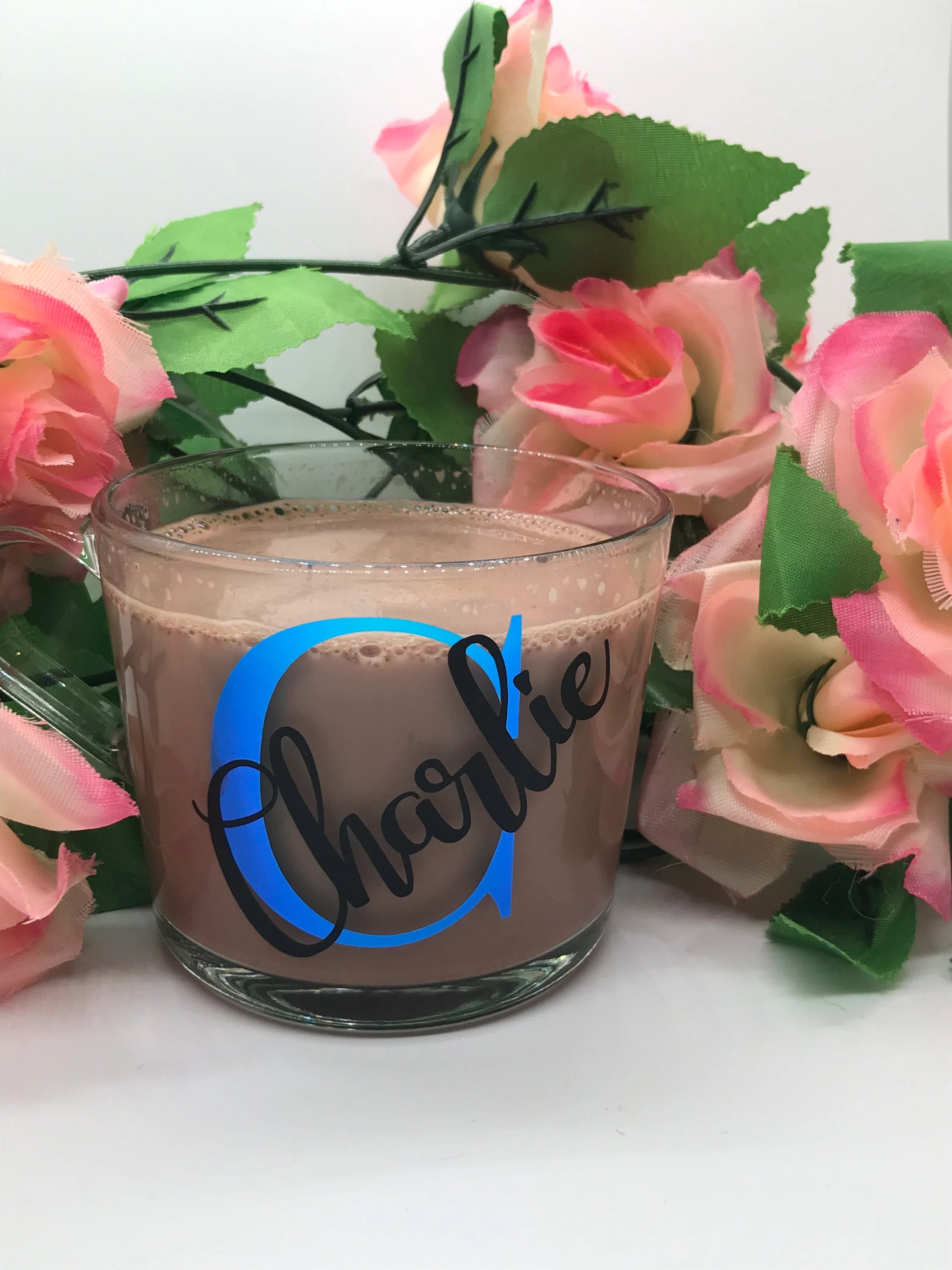 Glass mug with 'Charlie' design surrounded by pink flowers on a white background
