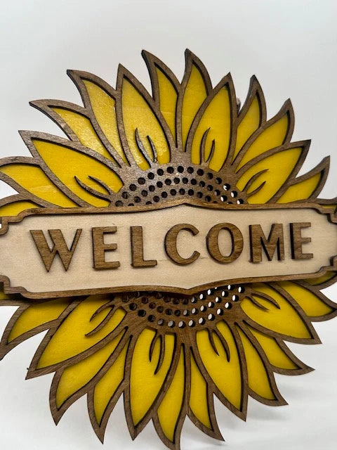 Decorative sunflower-shaped sign with 'WELCOME' text on a white background