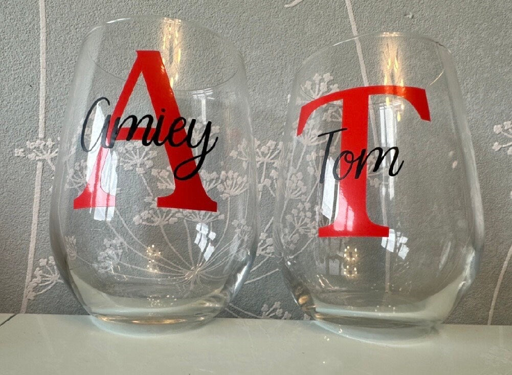 Two clear stemless glasses with red letters and names