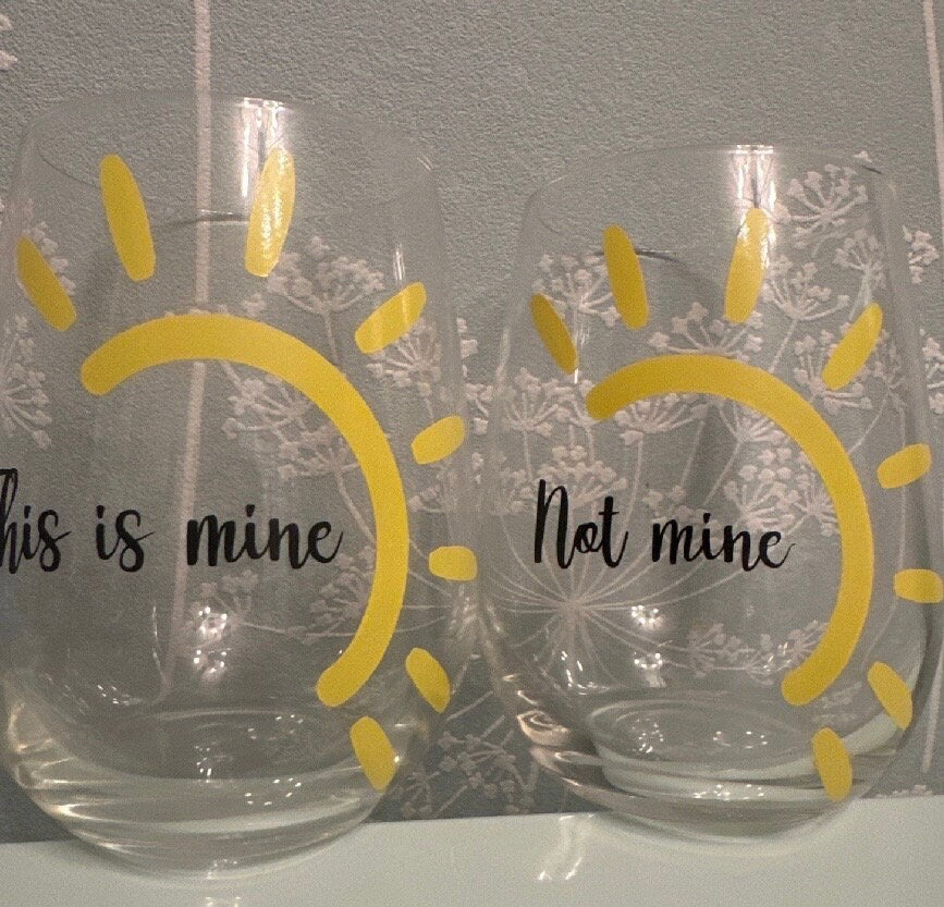 Two clear stemless glasses with custom yellow sun designs 