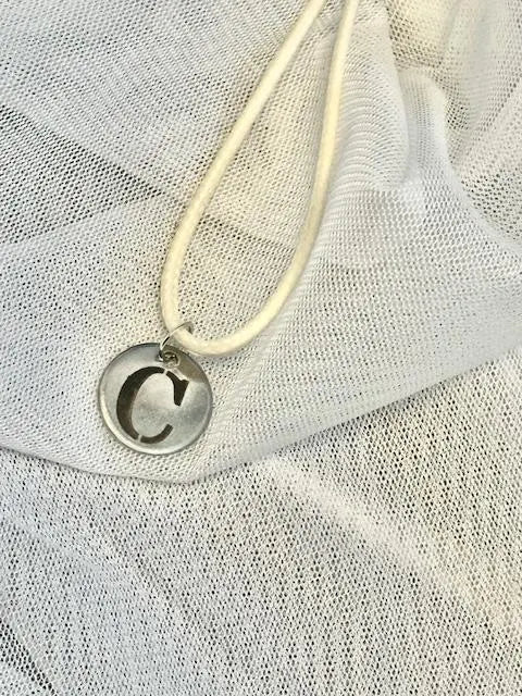 Stainless steel necklace with a round pendant on a textured white fabric background