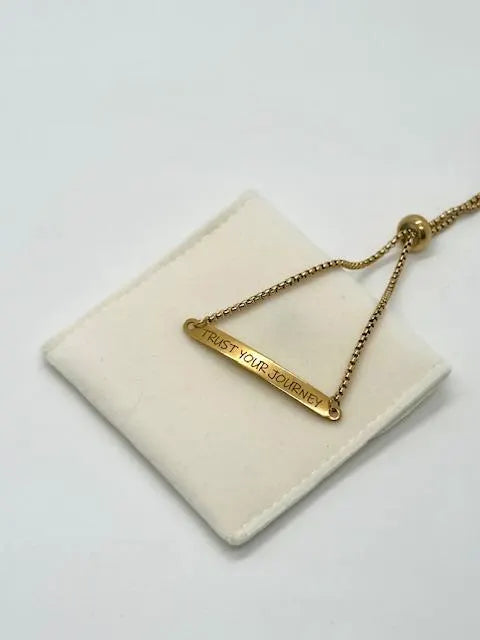 Gold stainless steel bracelet with 'Trust Your Journey' pendant on a white background