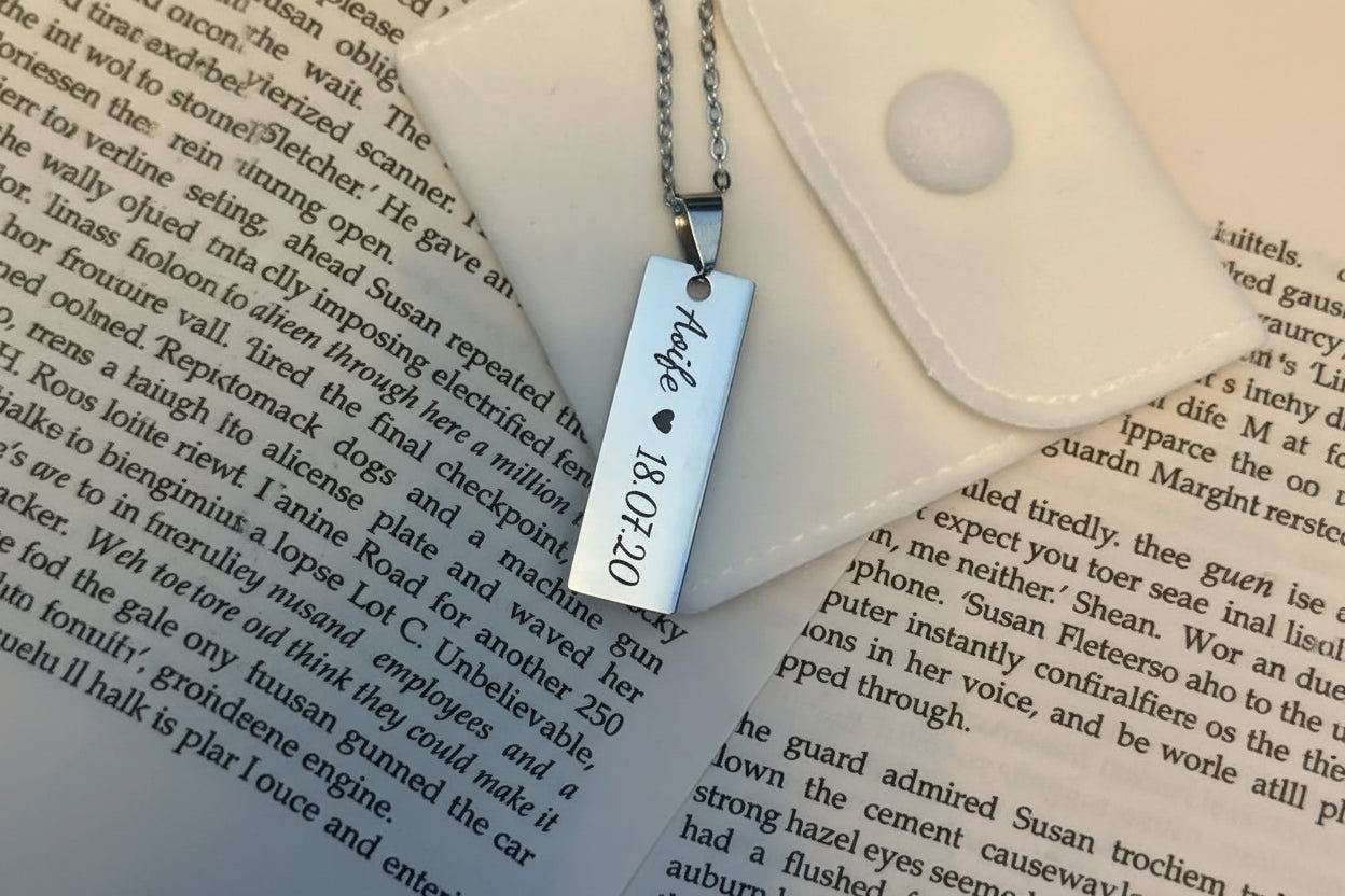 Silver stainless steel necklace with a rectangular pendant on an open book
