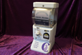 Capsule machine with a sign indicating it takes tokens and dispenses prizes.