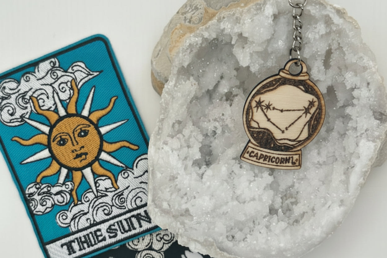 Zodiac keychain with star sign pendant on a crystal, tarot cards in the background