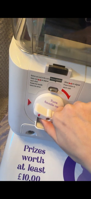 Hand turning the handle of the vending machine to win a prize