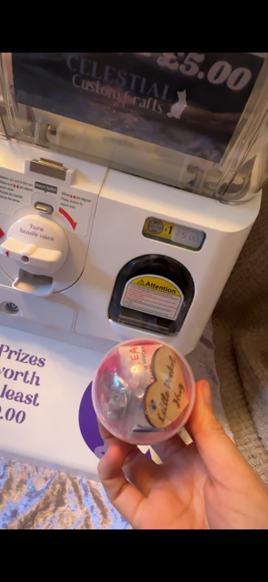 Hand holding a small pink capsule of prizes that has been won from the vending machine.