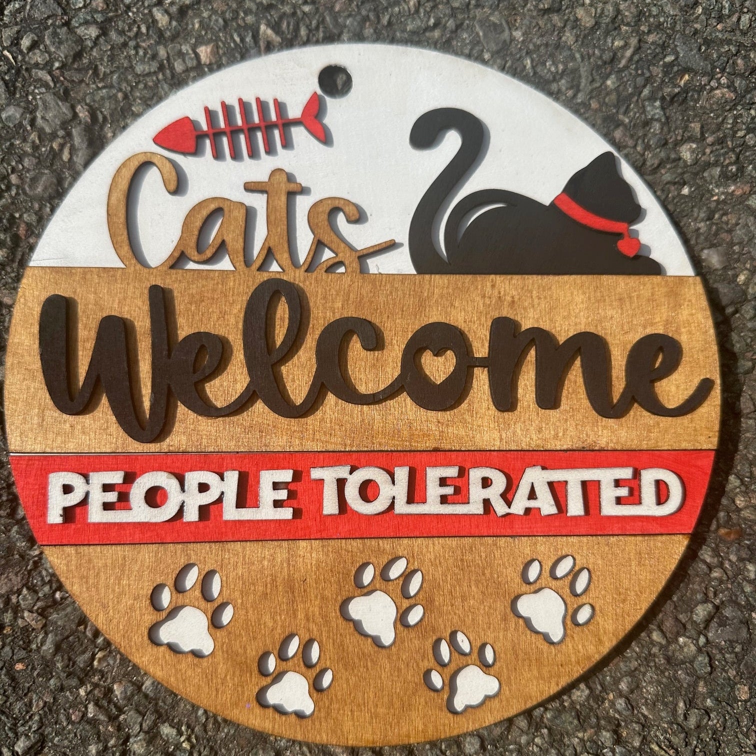 Round decorative sign with cat-themed text and graphics on